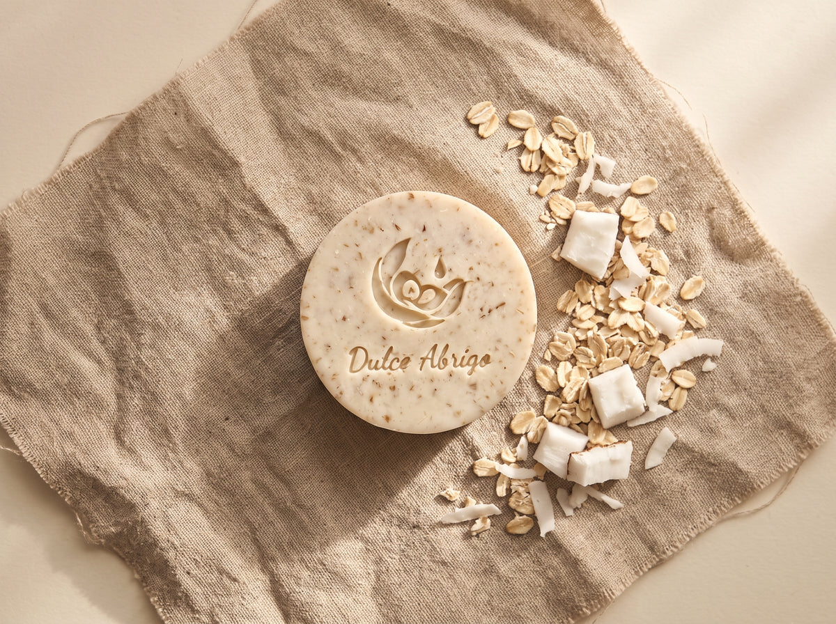 Jabón artesanal de avena y coco Dulce Abrigo sobre lino, con copos de avena y trozos de coco